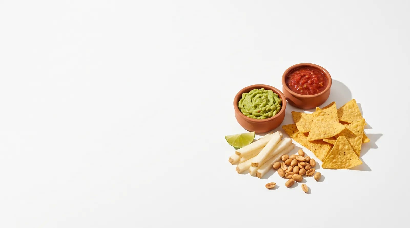 Tazones de guacamole y salsa con totopos, jícama con limón y cacahuates para botanear.
