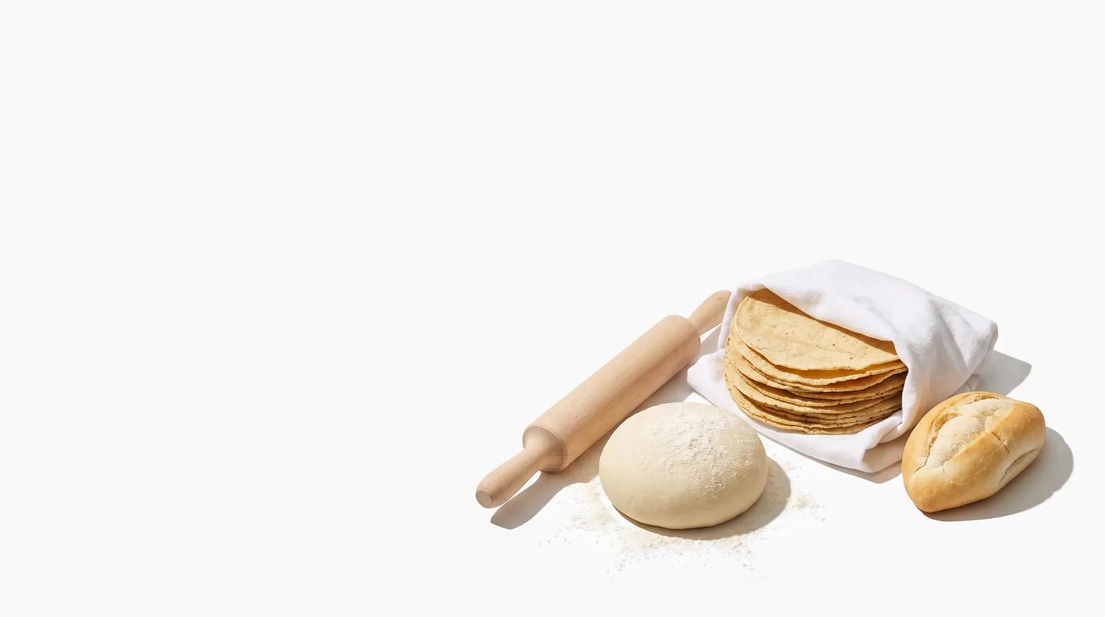 Tortillas de maíz recién hechas en una servilleta, una bola de masa, un rodillo y un bolillo.